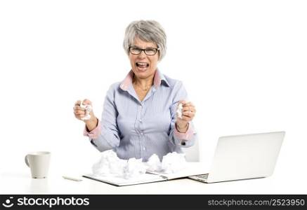 Stressed elderly woman working in the office with a laptop