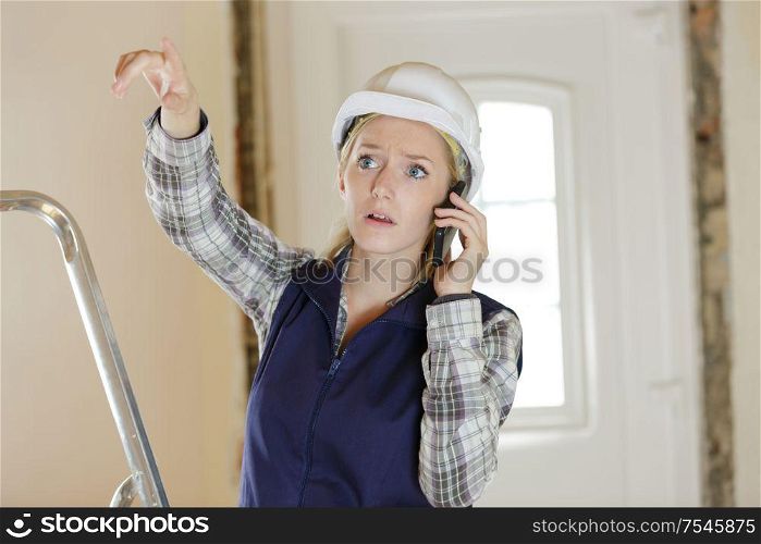 stressed female builder gesticulating while on telephone