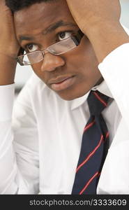 Stressed Male Teenage Student Studying In Classroom