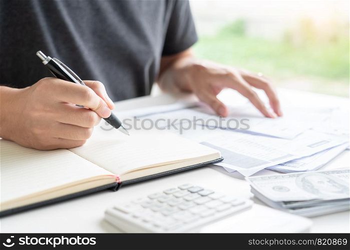 Stressed man calculating accounting holding a receipt checking bills, taxes, bank account balance counting money and making notes, check home expenses concept