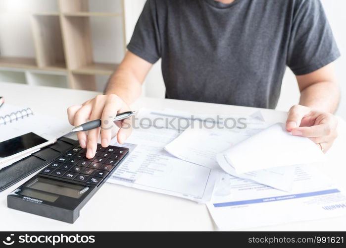 Stressed man calculating accounting holding a receipt checking bills, taxes, bank account balance counting money and making notes, check home expenses concept