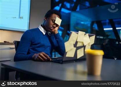 Stressed manager works on laptop, night office lifestyle. Male person at the table, dark business center interior on background, modern workplace. Stressed manager works on laptop, night office