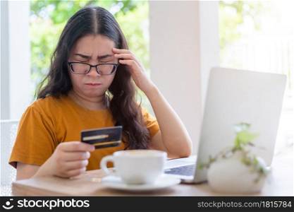 Stressed of freelance people business female casual show holding a credit card having a headache working with laptop computer in coffee shop like the background,for online shopping and payment