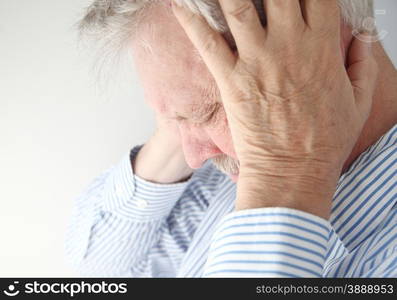 Stressed older man holds his head in both hands.