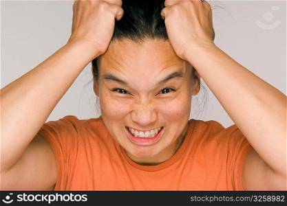 Stressed out Asian woman holding head with hands.
