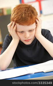 Stressed Schoolboy Studying In Classroom