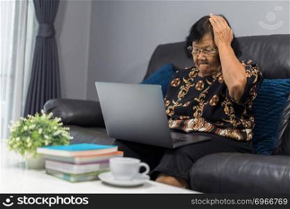 stressed senior woman working on laptop computer in living room