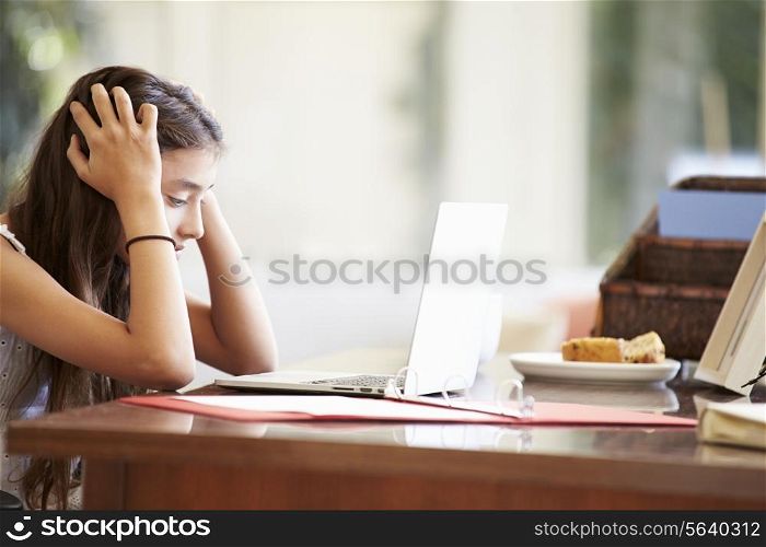 Stressed Teenage Girl Using Laptop On Desk At Home