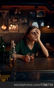 Stressed woman drinks alcohol beverage at the counter in bar. One female person in pub, human emotions, leisure activities, nightlife. Stressed woman drinks alcohol beverage in bar