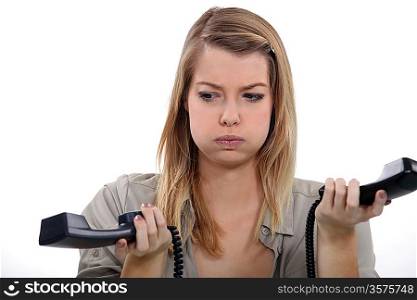 Stressed woman holding two telephones