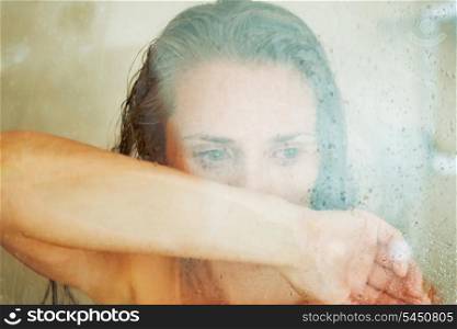 Stressed woman leaning on weeping glass shower door