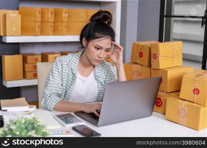 stressed woman working with her laptop computer and courier parcel box at home office