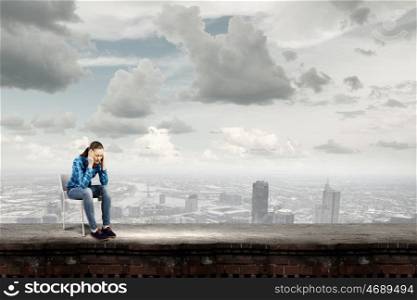 Stressed woman. Young troubled woman sitting on chair on building top