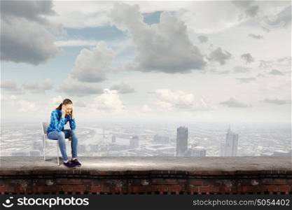 Stressed woman. Young troubled woman sitting on chair on building top