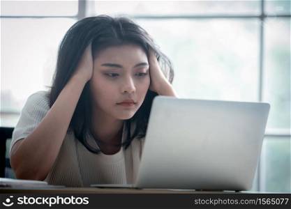 Stressed young asian woman using laptop, tired due to work
