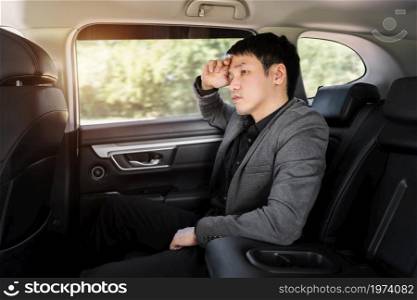 stressed young business man sitting in the back seat of car