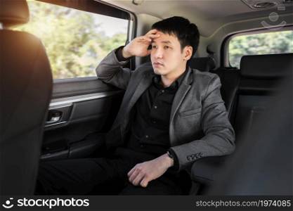 stressed young business man sitting in the back seat of car