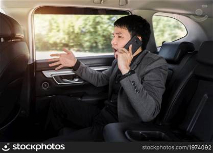 stressed young business man talking problem on a mobile phone while sitting in the back seat of car