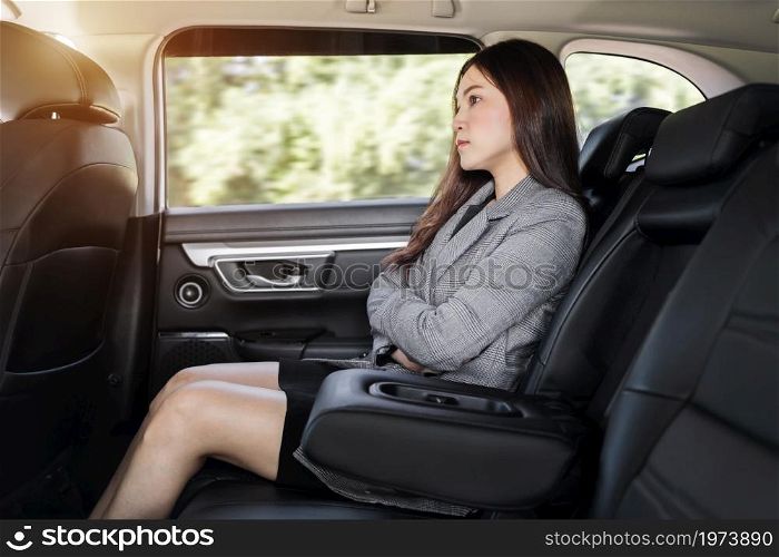 stressed young business woman sitting at the back seat of car