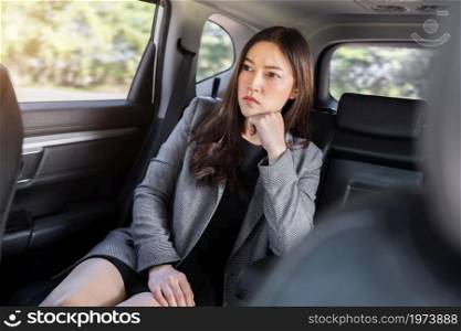 stressed young business woman sitting in the back seat of car