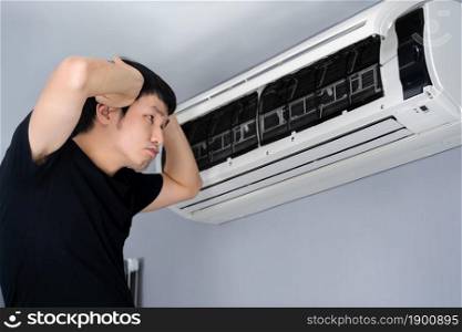 stressed young man has problem with the air conditioner at home