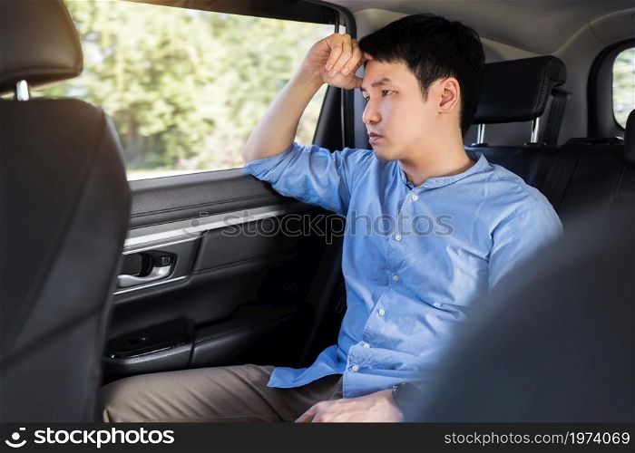 stressed young man sitting in the back seat of car