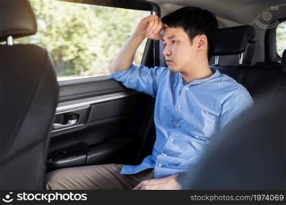 stressed young man sitting in the back seat of car