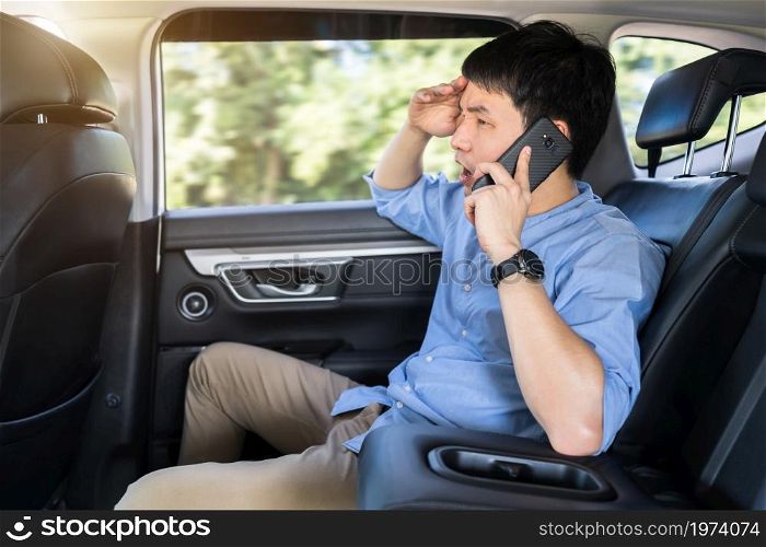 stressed young man talking problem on a mobile phone while sitting in the back seat of car