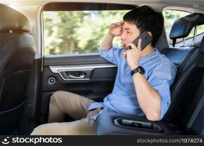 stressed young man talking problem on a mobile phone while sitting in the back seat of car
