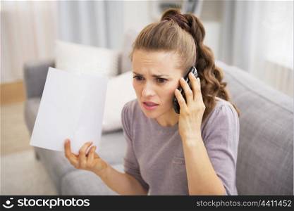 Stressed young woman holding letter and talking cell phone