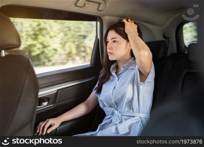 stressed young woman sitting in the back seat of car