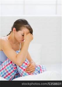 Stressed young woman sitting on bed