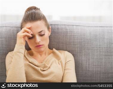Stressed young woman sitting on sofa