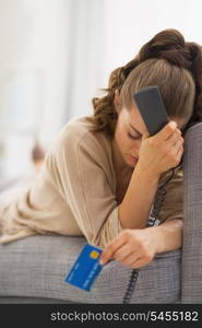 Stressed young woman with phone and credit card