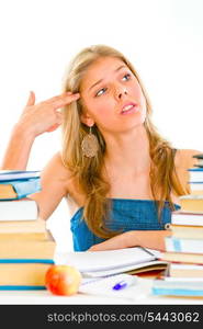 Stressful young girl sitting at table with books and holding gun shaped hand near head&#xA;