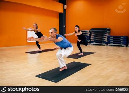 Stretching exercise, female yoga group, training with instructor, workout in gym. Yogi indoor. Female yoga group, training with instructor
