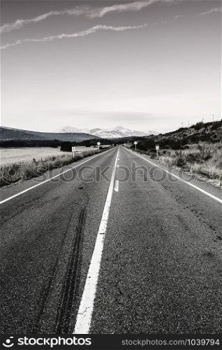 Stright asphalt road of Europe Peaks in Spain early morning. Spanish landscape at sunrise, hills, pastures, way and sunlight