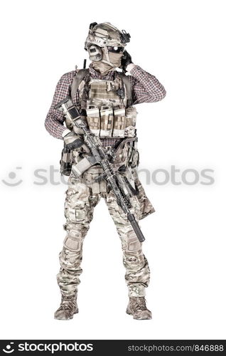 Strikeball enthusiast in checkered shirt wearing military ammunition, face mask, helmet and radio headset, tactical glasses, camo pants, armed service rifle and handgun studio shoot isolated on white. Softball player with military stuff studio shoot