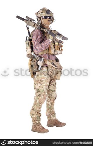 Strikeball enthusiast in checkered shirt wearing military ammunition, face mask, helmet and radio headset, tactical glasses, camo pants, armed service rifle and handgun studio shoot isolated on white. Softball player with military stuff studio shoot