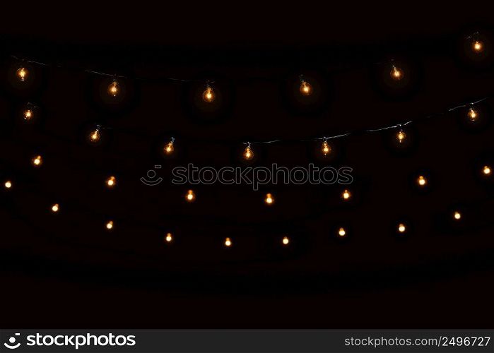 String lights glass bulbs garland with glowing spirals on dark black background
