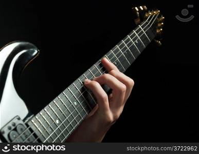 strings and guitarist hand playing guitar over black - shallow DOF with focus on hand