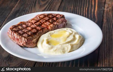 Strip steak with celery puree on white plate