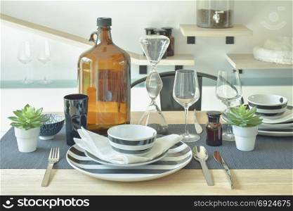 Striped chinaware, wine glass and bottle setting on wooden dining table