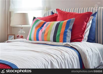 striped headboard with colorful pillows and striped pillow on white bed sheet