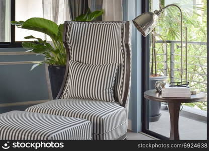 Striped high back easy chair with brass table lamp in the living room