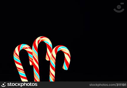 Striped lollipops candy canes on a black backdrop. Greeting card, holiday background with space for copy.. Festive Background With Lollipops