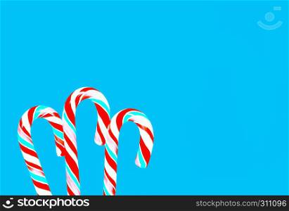 Striped red and turquoise lollipops candy canes on a blue backdrop. Greeting card, holiday background with space for copy.. Festive Blue Background With Lollipops