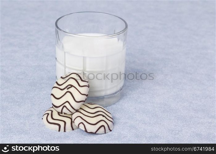 Striped white chocolate cookies with whole milk on blue table cloth