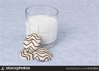 Striped white chocolate cookies with whole milk on blue table cloth