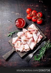 Strips of bacon on a cutting board. Against a dark background. High quality photo. Strips of bacon on a cutting board.